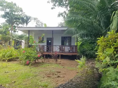a small house with a deck in a garden at Susan Bungalow#1 Bahía Drake, Corcovado Familia Amaya in San Pedrillo