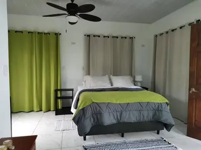 a bedroom with a bed with green curtains and a ceiling fan at Susan Bungalow#1 Bahía Drake, Corcovado Familia Amaya in San Pedrillo