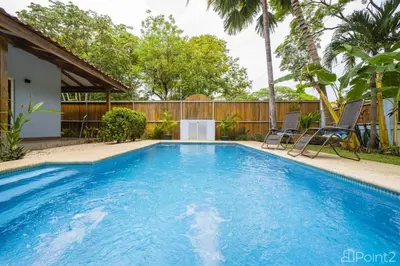 a swimming pool with blue water in a yard at Beautiful 2-BR House Steps from the Beach in Playa Flamingo