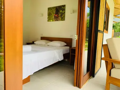 a bedroom with a bed with white sheets and a window at Bambura Bahia Villas in Uvita