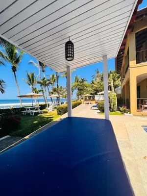 a blue table under awning in front of a house at The Backyard Beachfront Hotel in Jacó