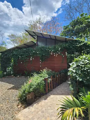 a red building with a fence and some plants at Montana Log Cabin in Rivas