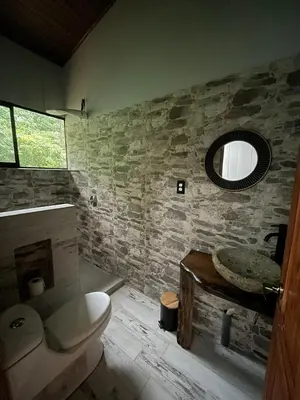 a bathroom with a toilet and a sink and a mirror at Montana Log Cabin in Rivas