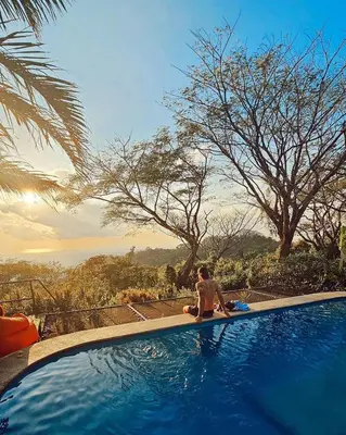 a man sitting on the edge of a swimming pool at Lodge Mirador - Great Swimming pool - Kitchen - BBQ - Netflix in Tajo Alto