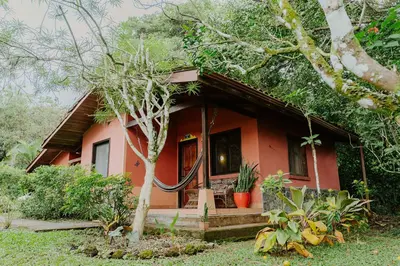 a small red house with a tree in front of it at Lodge Mirador - Great Swimming pool - Kitchen - BBQ - Netflix in Tajo Alto