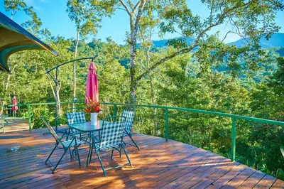 a table and chairs on a deck with a pink umbrella at Manoas in Uvita