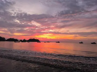 a sunset on the beach with boats in the water at Ocean View steps to the beach in Punta Leona