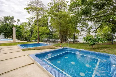 two swimming pools in a yard with trees at Ocean View steps to the beach in Punta Leona