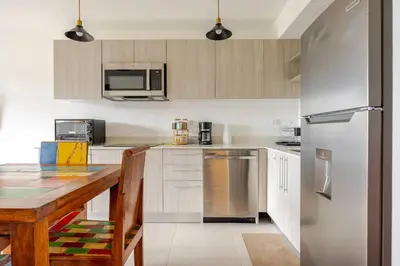 a kitchen with a wooden table and a stainless steel refrigerator at Ocean View steps to the beach in Punta Leona