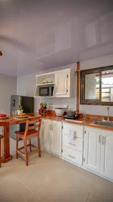 a kitchen with white cabinets and a wooden table at Villa Palmera-Fortuna in Fortuna