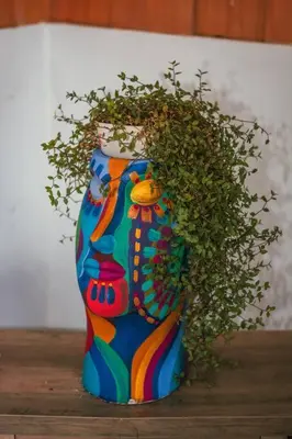 a colorful vase with a plant on a table at Cuki House in Quesada