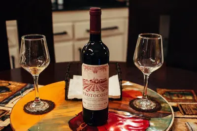 a bottle of wine sitting on a table with two wine glasses at Cuki House in Quesada