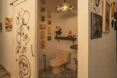 a bathroom with a toilet and some pictures on the wall at Cuki House in Quesada