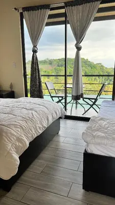 a bedroom with two beds and a balcony with a view at Hotel Bar Restaurante IL Rifugio in Poás