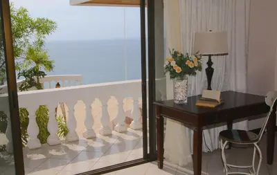 a room with a desk and a balcony with the ocean at The Lighthouse Ocotal in Coco