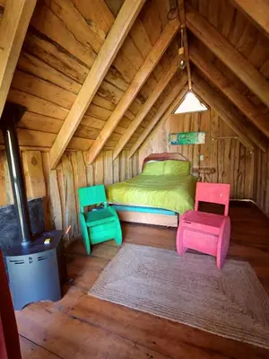 a room with a bed and two chairs in a attic at Tipi Cabécar in Heredia