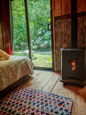 a fireplace in a room with a bed and a rug at Tipi Maleku in Heredia