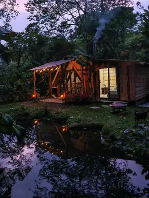 a cabin in the woods next to a pond at Tipi Maleku in Heredia
