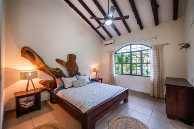 a bedroom with a bed with a large wooden headboard at Villa Cascada by Vacation Pura Vida in Esterillos