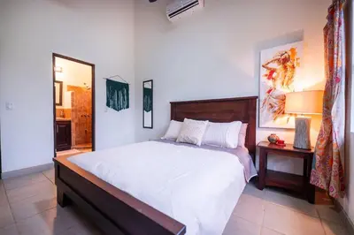 a bedroom with a bed and a table and a mirror at Villa Cascada by Vacation Pura Vida in Esterillos