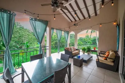 a living room with a table and chairs on a balcony at Villa Cascada by Vacation Pura Vida in Esterillos