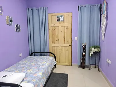 a bedroom with a bed and a dog standing in front of a door at Brand New Descanso del Perezoso in Manuel Antonio