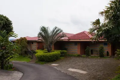 a house with a palm tree next to a road at Hotel Linda Vista in Fortuna