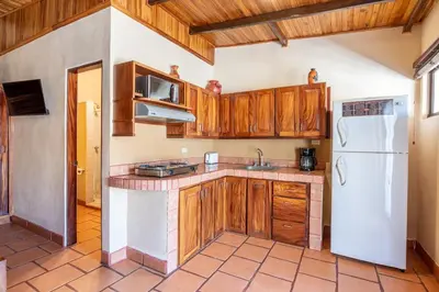a kitchen with wooden cabinets and a white refrigerator at BP Surf Hotel in Playa Grande