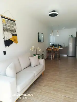 a living room with a white couch and a kitchen at Valu in Puntarenas