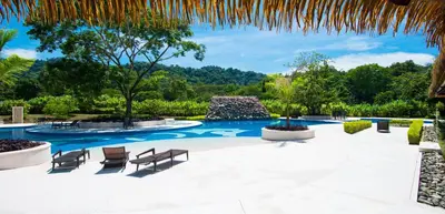 a swimming pool with two chairs and a resort at Ciudad del Mar 126 condo in Jacó