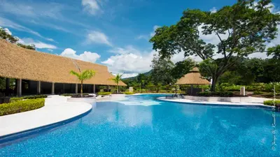 a pool at a resort with thatched umbrellas at Ciudad del Mar 126 condo in Jacó