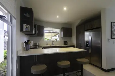 a kitchen with a counter and a refrigerator and stools at Ciudad del Mar 126 condo in Jacó