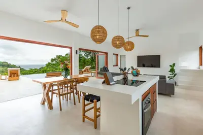 a kitchen and living room with a table and chairs at Elegant Ocean View Villa Serena in Cóbano