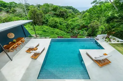 a swimming pool with two lounge chairs and a swimming pool at Elegant Ocean View Villa Serena in Cóbano