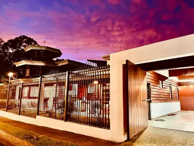 a fence in front of a building with a purple sky at Casa Victoriana Aeropuerto in San Juan Arriba