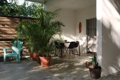 a patio with a table and chairs and palm trees at Casa IGUANA in Santa Teresa Beach