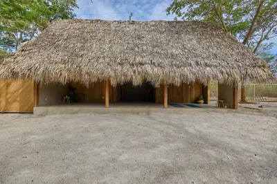 a hut with a thatched roof on top of it at SURÁ Playa Negra in Playa Negra