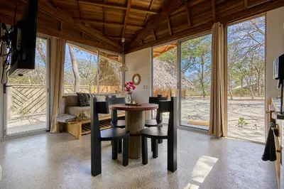 a living room with a table and chairs and windows at SURÁ Playa Negra in Playa Negra