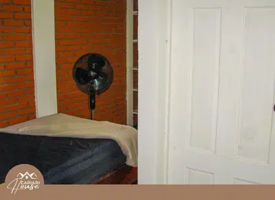a room with a bed and a fan next to a brick wall at Private rooms, 10 min from SJO Airport in Ciudad Cariari