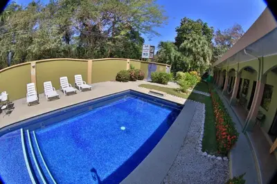 a swimming pool in a yard with chairs and a house at Pitaya Lodge in Potrero