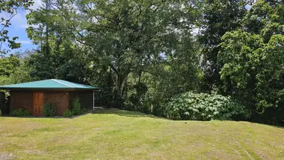 a small building with a blue roof in a yard at El Castillo Harmony in El Castillo de La Fortuna
