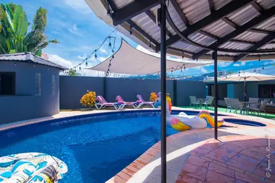 a swimming pool with chairs and an umbrella at Casa Plomo - 10 bed, 5 bdrm - One Block from Clubs in Jacó