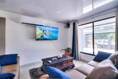 a living room with a couch and a tv at Casa Plomo - 10 bed, 5 bdrm - One Block from Clubs in Jacó