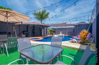 a patio with a table and chairs next to a swimming pool at Casa Plomo - 10 bed, 5 bdrm - One Block from Clubs in Jacó