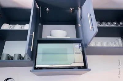 a microwave in a kitchen with blue cabinets at Casa Plata & Casa Plomo in Jacó