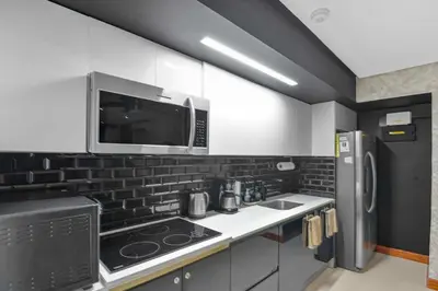 a kitchen with white cabinets and a microwave and a refrigerator at Luxury 2BR condo in Nautilus, Místico in Parrita