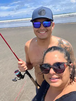 a man and a woman holding a fishing pole on the beach at Ola Bonita BeachFront Apart Hotel in Playa Hermosa