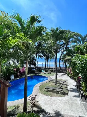a resort with a swimming pool and palm trees at Ola Bonita BeachFront Apart Hotel in Playa Hermosa