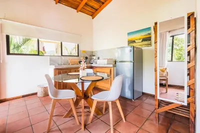 a kitchen with a table and chairs and a refrigerator at Ola Bonita BeachFront Apart Hotel in Playa Hermosa