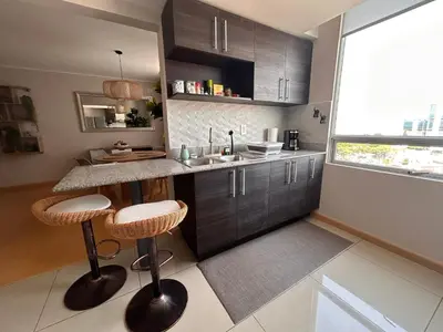 a kitchen with a counter with stools and a sink at Moderno apartamento totalmente equipado in San José